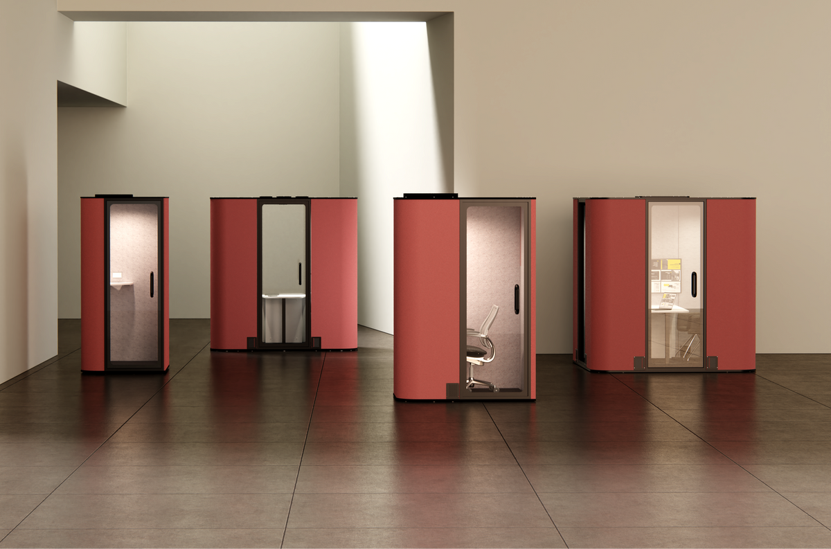 Four compact privacy pods in salmon and black are arranged in a minimalist interior space with beige walls and dark brown tiled flooring.